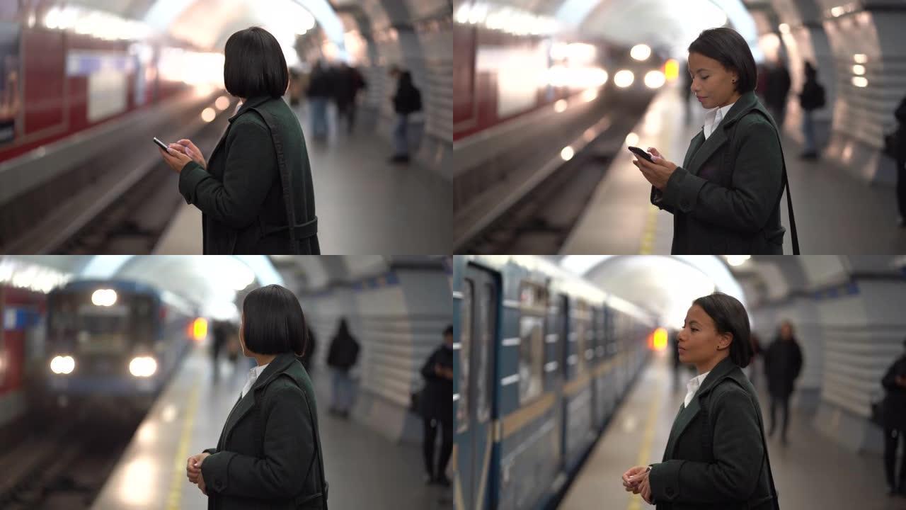 严肃的非洲女商人在等待地铁列车时在地铁站台上使用智能手机