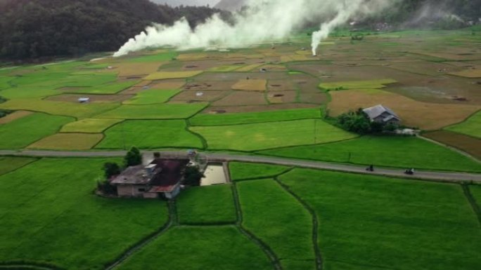 无人机镜头-武吉丁吉附近一个村庄的稻田视图，农民在收割水稻后燃烧稻草