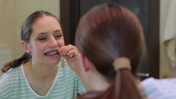 女孩用牙套在牙齿上涂上橡皮筋。正畸治疗