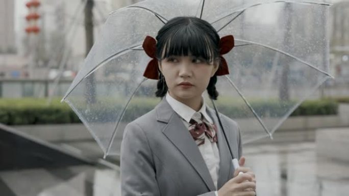 日本女学生身穿校服站在雨中手持透明雨伞