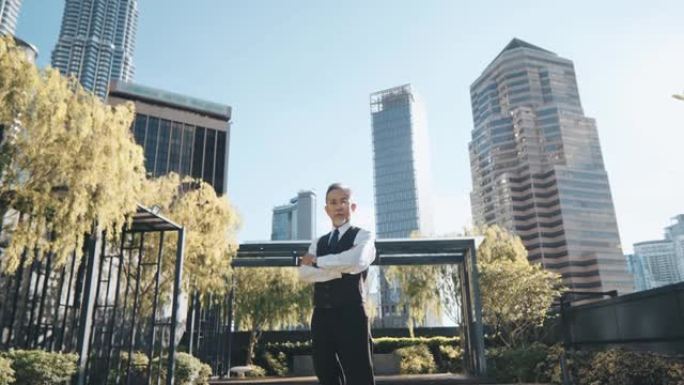 亚洲中国公司首席执行官双臂交叉站在城市办公楼的屋顶上。