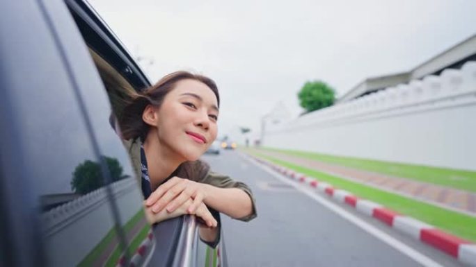 亚洲美女旅行者打开车窗面对外面的空气。迷人的年轻女性旅游背包客在美丽的城市旅行，花时间在泰国的假日度