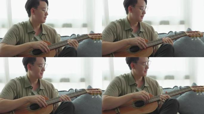 一名亚洲男子弹吉他和音乐愉快地放松自己的思想