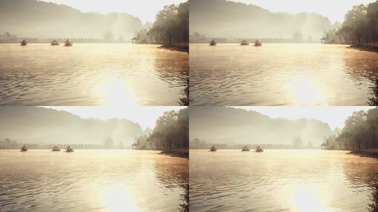 泰国北部湄宏顺班拉泰国村背景上的传统中式船，在清晨的阳光下雾蒙蒙的河水湖上日出