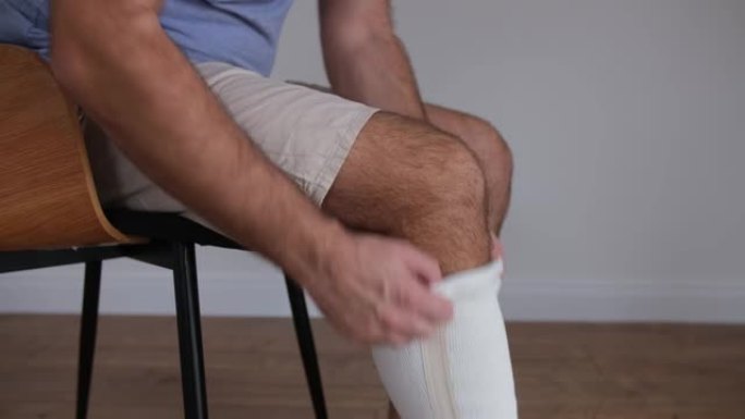 高加索男性戴上弹性膝盖稳定器带以从受伤中恢复过来