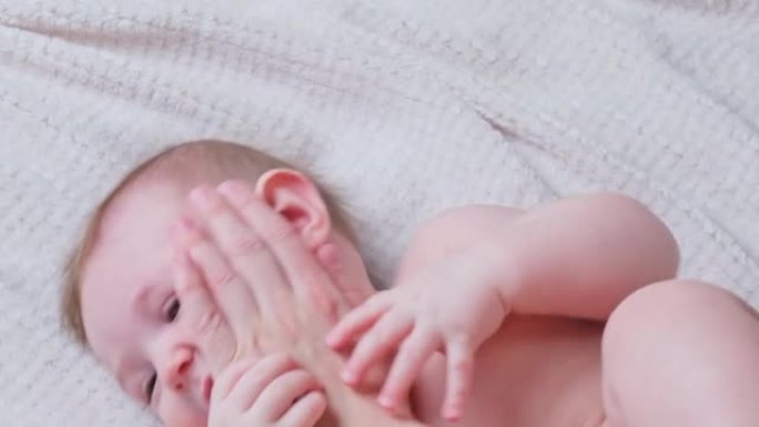 母亲用躺在床上的棉签清洁婴儿蹒跚学步的男孩的耳朵。妈妈清洁孩子的耳廓，一个八个月大的孩子