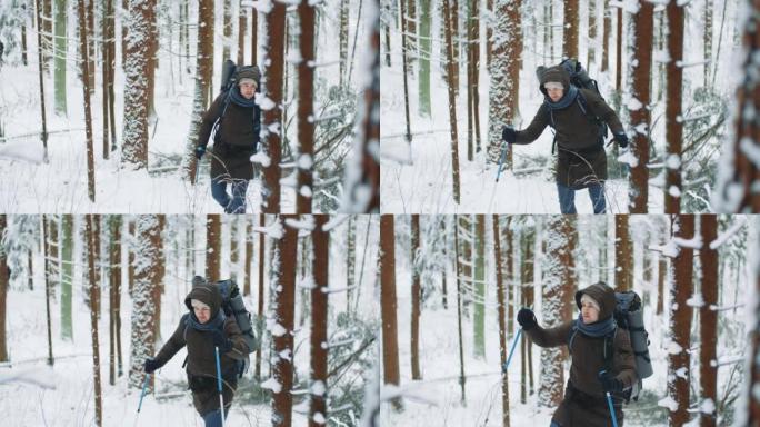 手持射击年轻的徒步旅行者在白雪覆盖的冬季森林中行走。男性高加索旅行者带着徒步旅行背包在森林里用杆子爬