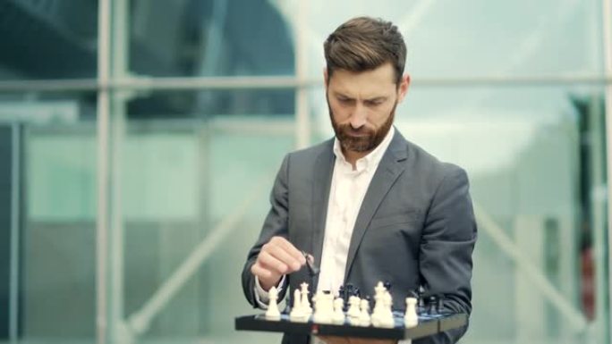 一位成功的认真商人拿着棋盘的肖像，手里拿着国际象棋。