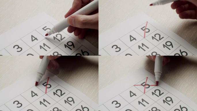 人的手用红笔在纸质日历上写下第五天。