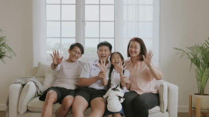 亚洲家庭看着相机，挥舞着手。