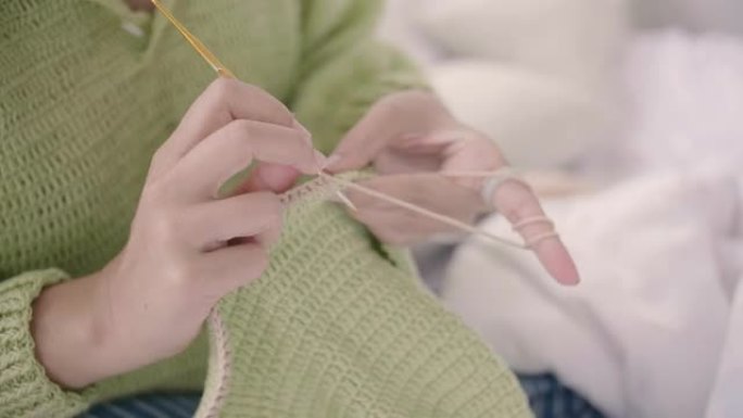 年轻女子享受她的生活和闲暇时间在卧室钩针编织。