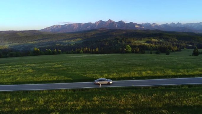 日落时在空旷的道路上鸟瞰山路和豪华轿车。在大塔特拉山脉的背景下。概念: 山区度假，家庭公路旅行，旅行