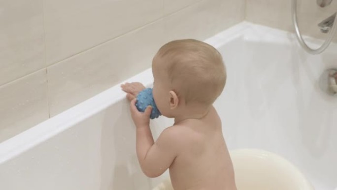 可爱的小孩洗澡和玩玩具，孩子玩洗澡玩具橡胶球，10个月大的男婴在干净的水中洗澡特写。儿童卫生和保健的