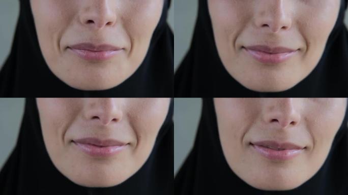 一个穿着黑色头巾的女人的嘴唇特写，一个穆斯林女人美丽的微笑。伊斯兰世界的善良与和平概念。女人嘴的特写
