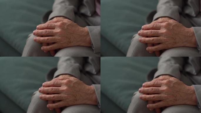 一个面目全非的老妇的手的特写。成熟的女人双手交叉在皱纹和膝盖上的老年斑。老年