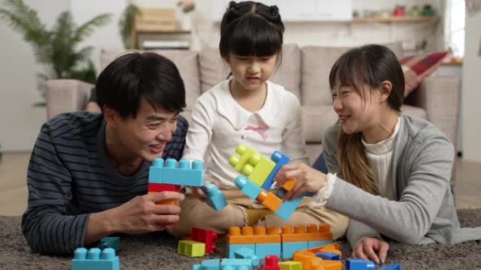 孩子般的亚洲妈妈和爸爸用玩具积木玩格斗游戏的慢动作。生气的女儿正在中间建立自己的工作，并推开男人的手