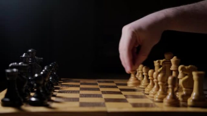 棋盘游戏中带着棋子的人手。象棋游戏的开场用白王棋子的e2-e4，黑色背景上的复制空间