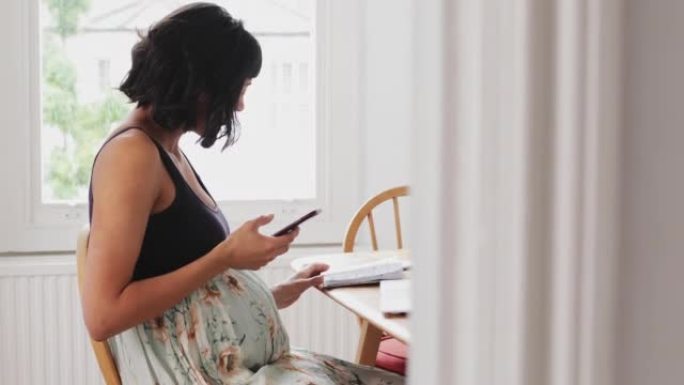 孕妇在餐桌上使用智能手机