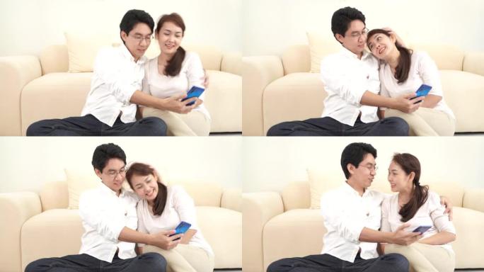 快乐的亚洲夫妇男人和女人在家里的客厅与朋友和家人使用智能手机面对面视频通话。呆在家里检疫，社交距离，