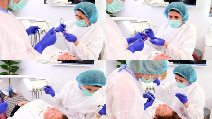 牙医在现代口腔医学诊所工作，助手帮助女性患者治疗牙齿。