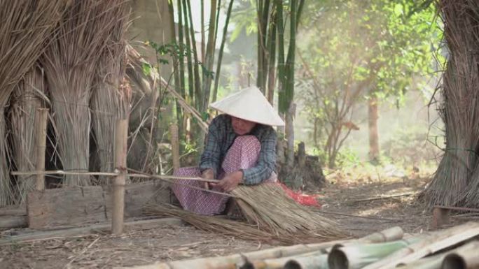 亚洲生活老奶奶在户外工作。老太太老人严重生活在泰国农村的农村。编织材料草屋顶毛边竹制。