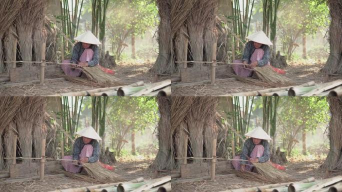 亚洲生活老奶奶在户外工作。老太太老人严重生活在泰国农村的农村。编织材料草屋顶毛边竹制。