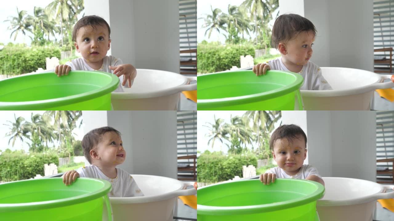 一个漂亮的婴儿在他家后院的白色盆里洗。幼儿卫生和日常洗澡，以改善婴儿的健康。孩子认识世界，学会认识这