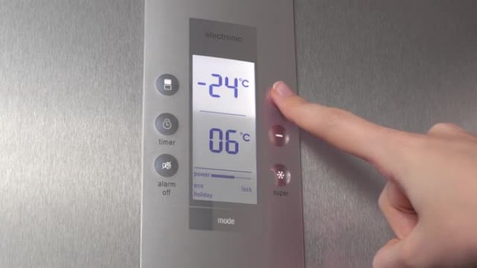 女人的手按下冰箱中的按钮，降低温度。