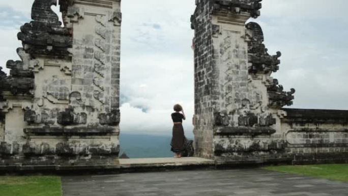 一位女博主游客在巴厘岛天堂之门的一个美丽地方的智能手机上拍照。至今保存的令人难以置信的宗教建筑