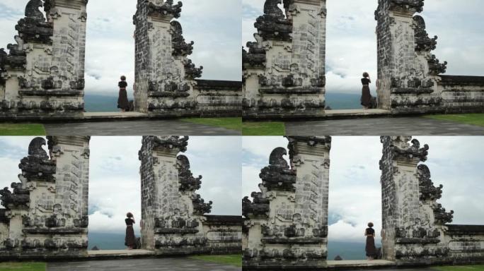 一位女博主游客在巴厘岛天堂之门的一个美丽地方的智能手机上拍照。至今保存的令人难以置信的宗教建筑