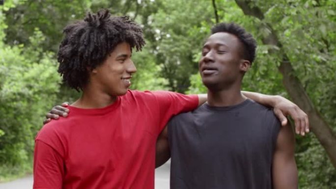 两个黑人千禧一代站在户外拥抱和交谈