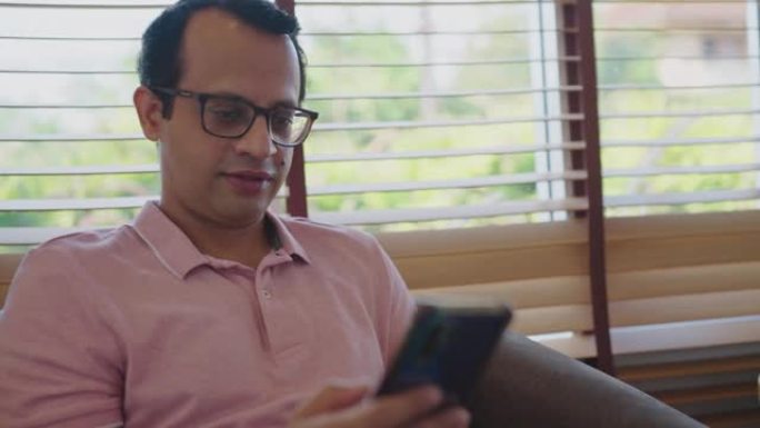 印度男子使用智能手机，在家中享受客厅。