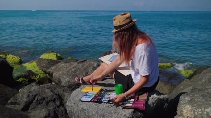 女画家画帆船游艇坐在海岩上