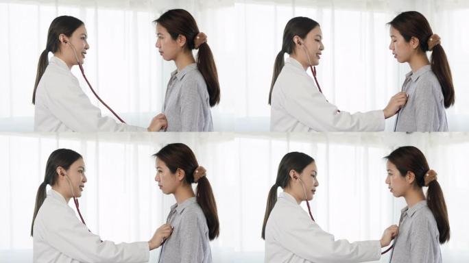 4K，一名亚裔女医生用听诊器对着病人的胸部，听心音，了解病人的病情。概念健康与医学
