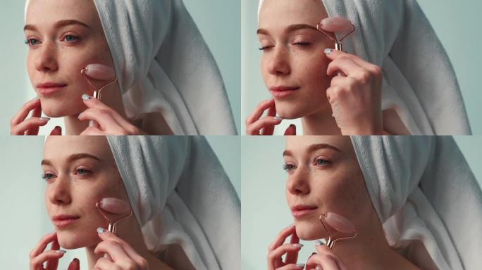 一个女人头上有毛巾的特写肖像，脸上有玉辊。年轻化治疗。面部皮肤治疗。面部护肤。