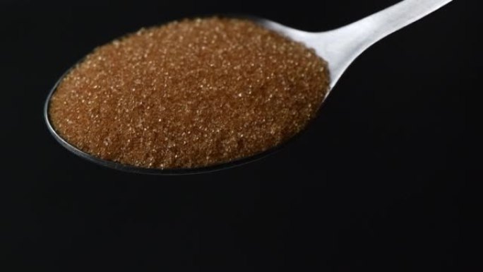 慢动作关闭从勺子上掉下来的红糖或赤藓糖醇糖。倒满汤匙砂糖的特写宏观。