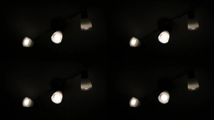 在可能是由于战争造成的停电期间，三个灯泡在昏暗的灯光下闪烁和嗡嗡作响。黑暗的环境，灯开和关，有电力问