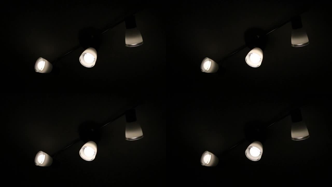在可能是由于战争造成的停电期间，三个灯泡在昏暗的灯光下闪烁和嗡嗡作响。黑暗的环境，灯开和关，有电力问