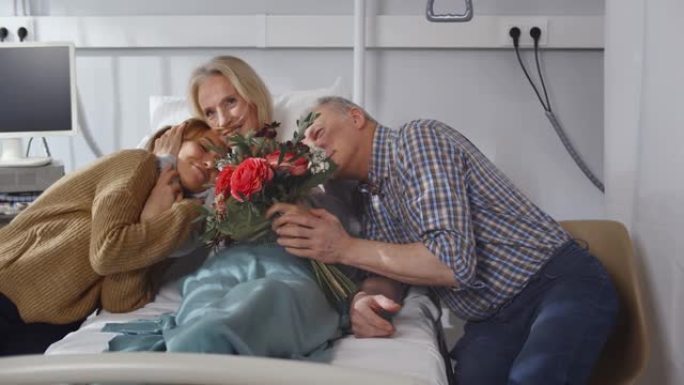 快乐的高级丈夫和小女儿探视和欢呼躺在医院病房的妇女