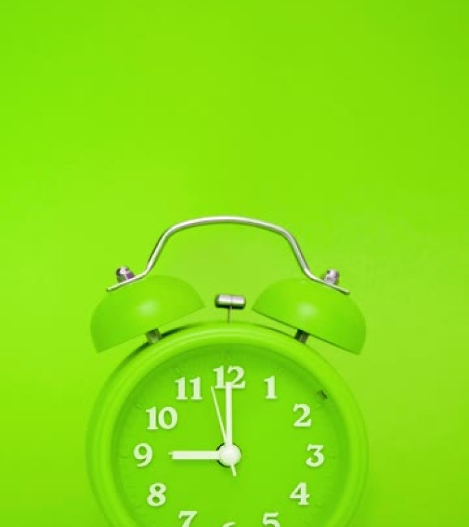 绿色背景上的绿色经典闹钟在上午9点响起 -- 带声音的垂直视频