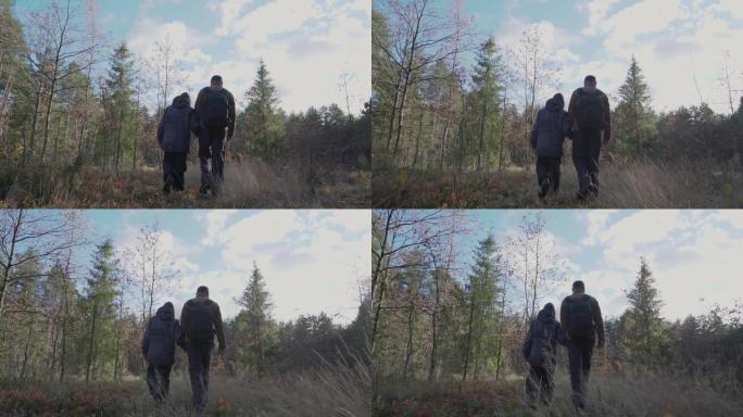 背着背包的爸爸用手抱着儿子，慢慢地穿过森林