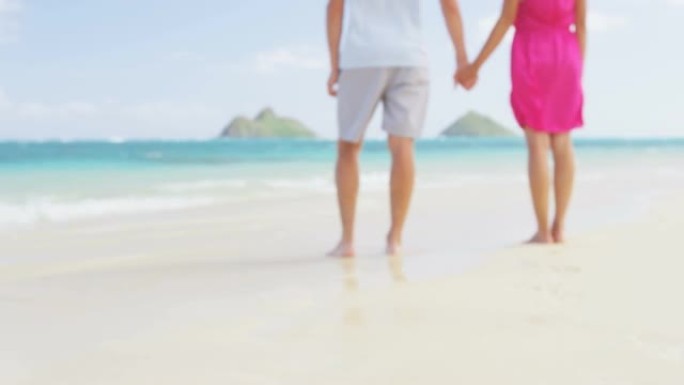 海滩上牵着浪漫的新婚夫妇。背景不集中和模糊。在美国夏威夷瓦胡岛的Lanikai海滩上，女人和男人在暑