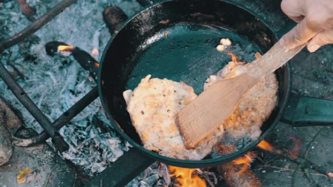 在室外火上的煎锅里用油炸猪排，煮肥肉