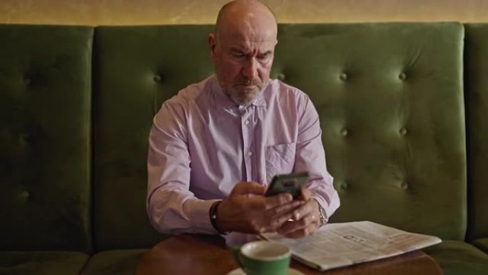 现代高加索高级男子在咖啡店使用手机