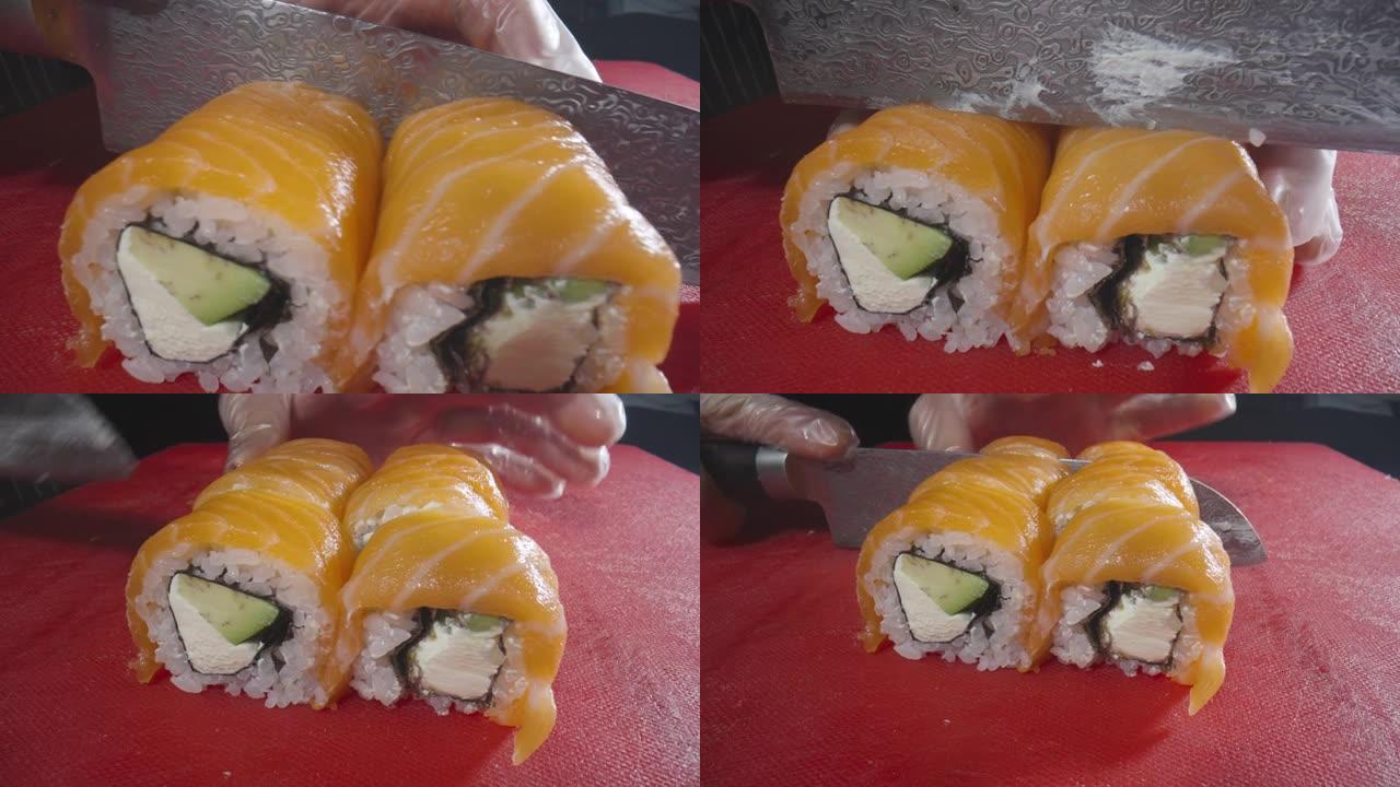 烹饪寿司卷的过程费城特写。寿司大师用锋利的刀将卷切成碎片。传统的日本料理搭配海鲜和鱼。亚洲美食。寿司