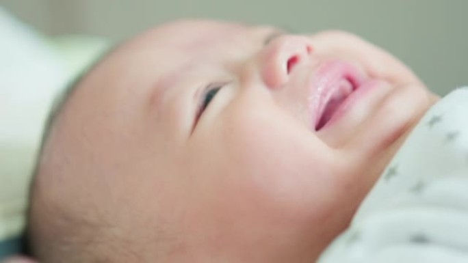 脸部特写可爱的亚洲新生婴儿躺在白色床上玩耍看着相机笑着开心的脸。天真的小新婴儿可爱。父母身份和母亲节