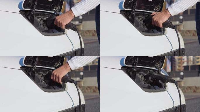 一名男性司机将电动汽车连接到电源系统为汽车电池充电