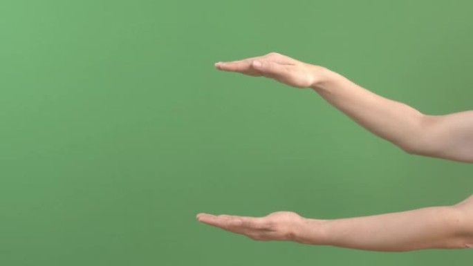 女人牵着手，在手掌之间显示出虚拟和无形的东西。女性手在绿屏色键背景上扩展广告复制空间