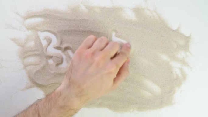 俯视图在沙滩上画。高加索人用米色沙子书写文字。度假和旅行。海滩度假。沙画。来自天然材料的创造力。