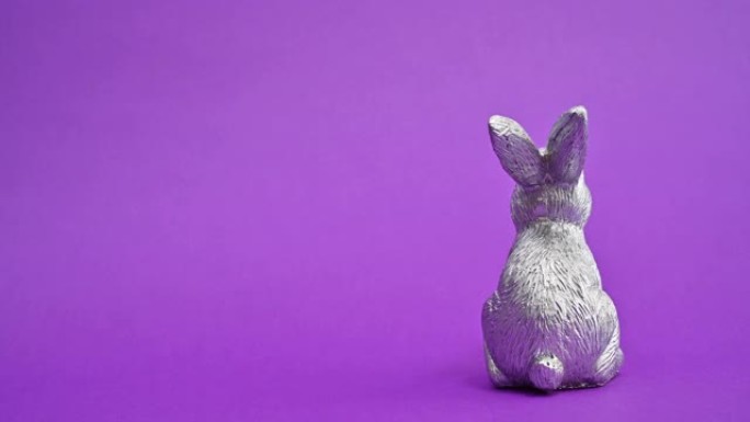 陶瓷银色复活节兔子在充满活力的紫色背景上旋转。停止运动